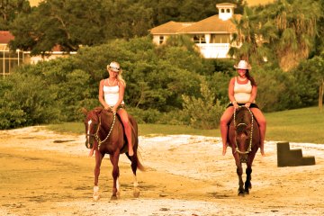 Two guides riding horses on the beach in Florida